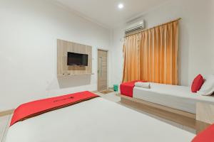 um quarto com uma cama grande e uma televisão em RedDoorz Syariah near Taman Bekapai 2 em Klandasan Kecil