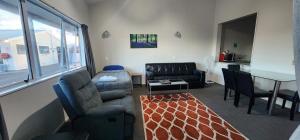 ein Wohnzimmer mit einem Sofa, Stühlen und einem Tisch in der Unterkunft Acorn Estate Motel in Masterton