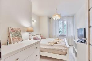 ein weißes Schlafzimmer mit einem Bett und einem Fernseher in der Unterkunft Apartament 70m2 przy parku Zdrojowym, plaża, centrum. in Świnoujście