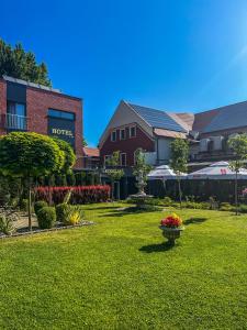 une cour verdoyante avec une maison et des fleurs dans une cour dans l'établissement Hotel Adria, à Ruda Śląska