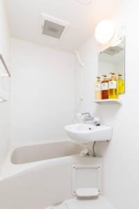 uma casa de banho branca com um lavatório e um espelho em 楓ホテル402 em Osaka