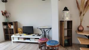 un soggiorno con sgabelli, tavolo e TV di Gîte Du Soleil Maison lumineuse avec terrasse solarium parking privé a Sorède
