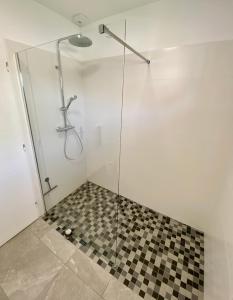 a shower with a glass door and a checkered floor at Les Rochers - Raffinement boisé & proche mer - Sérénité in Brétigny