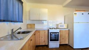 a kitchen with a sink and a white refrigerator at Ocean Views in Burrum Heads