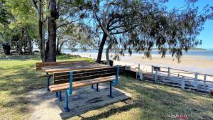 un banco del parque sentado junto a una playa en San Marco Villa Close To Beach, en Burrum Heads