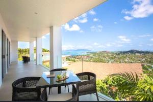 サムイ島にあるCobalt Suite Sea View Apartmentのバルコニーにテーブルと椅子が置かれたパティオ