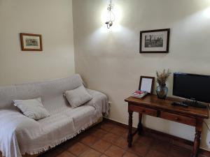 uma sala de estar com um sofá e uma mesa com uma televisão em La Hostería de Oropesa em Oropesa