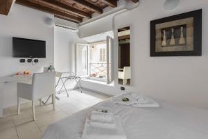Habitación blanca con cama, escritorio y TV. en Flowers Apartments, en Roma