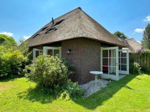 a small brick house with a table in a yard at Uylkenshof safaritenten en natuurhuisjes in Epe