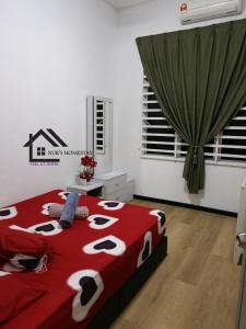 a bedroom with a bed with a red and white comforter at Nur's Homestay in Kuantan