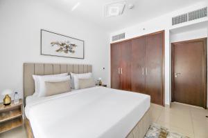 a bedroom with a white bed and a wooden cabinet at Designer 1BR 29 Boulevard Downtown Dubai Near Burj Khalifa in Dubai
