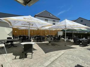 un patio avec des tables, des chaises et des parasols dans l'établissement Hotel Roma, à Merzig