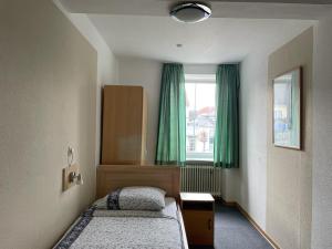 a bedroom with two beds and a window with green curtains at Hotel Roma in Merzig