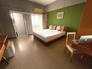 1 dormitorio con cama y escritorio con ordenador portátil en Plai And Herbs Suvarnabhumi Airport, en Lat Krabang