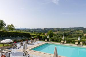 una piscina con sedie a sdraio e ombrelloni di Suite Orcio a San Gimignano