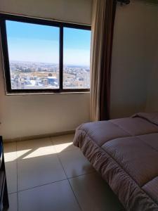 a bedroom with a bed and a large window at Omaima Hotel Apartments in Amman