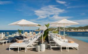 a row of white lounge chairs and umbrellas on a roof at INNSiDE by Meliá Ibiza Beach in San Antonio Bay