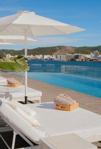 2 sedie a sdraio e un ombrellone accanto alla piscina di INNSiDE by Meliá Ibiza Beach a Baia di Sant'Antoni