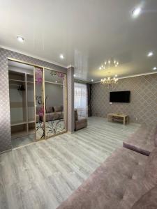 ein Wohnzimmer mit einem Sofa und einem Flachbild-TV in der Unterkunft VIP квартира в Центре, 2 комнаты in Qostanai