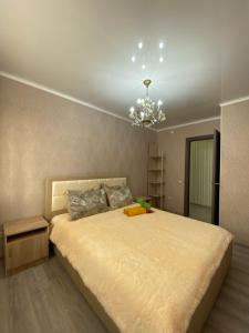 Un dormitorio con una cama grande y una lámpara de araña. en VIP квартира в Центре, 2 комнаты, en Kostanái
