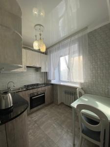 a kitchen with a table and a stove and a window at Квартира в Центре, 2 комнаты in Kostanay +6 photos