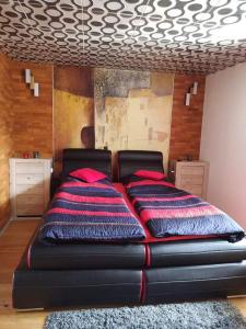 a black bed with red pillows in a bedroom at Ruheoase Nähe Wien in Wetzleinsdorf