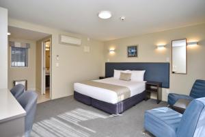 a hotel room with a bed and two chairs at The Riverstone in Rangiora