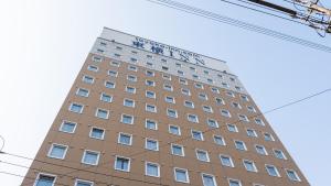 a tall building with a sign on top of it at Toyoko Inn Tsu eki Nishi guchi in Tsu