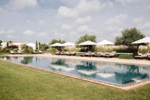 uma piscina com cadeiras e guarda-sóis num quintal em Torralbenc, a Small Luxury Hotel of the World em Cala'n Porter