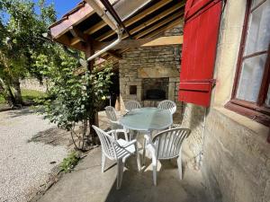 una mesa y sillas en un patio con chimenea en L'Ouvrée, chaleureux en famille ou entre amis, en Saint-Aubin