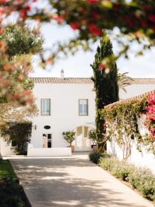 a white house with flowers in front of it at Torralbenc, a Small Luxury Hotel of the World in Cala en Porter