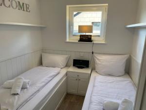 2 Betten in einem kleinen Zimmer mit Fenster in der Unterkunft Ferienwohnung Dünenblick in Westerland