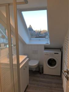 ein Bad mit einem WC, einem Waschbecken und einem Fenster in der Unterkunft Ferienwohnung Dünenblick in Westerland