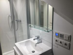 ein Bad mit einem Waschbecken und einer Dusche mit einem Spiegel in der Unterkunft Ferienwohnung Dünenblick in Westerland