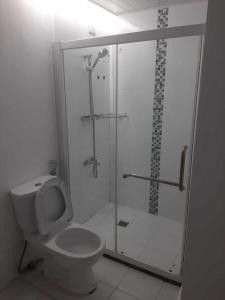 een badkamer met een douche, een toilet en een glazen deur bij Cebu City Apple One Banawa Heights in Cebu City