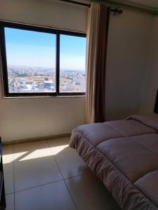 a bedroom with a bed and a large window at Omaima Hotel Apartments in Amman