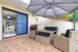 un patio con mesa, sillas y sombrilla en Soleluna apartment en Castelsardo