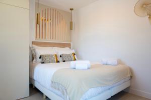 um quarto com uma grande cama branca com almofadas em Superbe studio avec balcon vue mer à 100m de la plage em Saint-Tropez