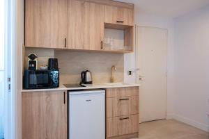 a kitchen with wooden cabinets and a white refrigerator at Superbe studio avec balcon vue mer à 100m de la plage in Saint-Tropez