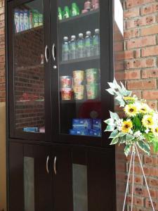 a black cabinet with drinks in it with a bouquet of flowers at JQ BL Hotel, Ipoh in Ipoh