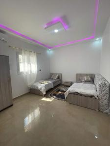 2 camas en una habitación con luces moradas en el techo en Diar ayat V1, en Taguermess