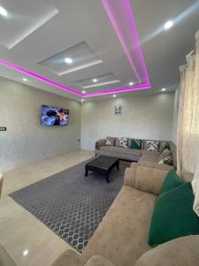 una sala de estar con luces moradas en el techo en Diar ayat V1, en Taguermess