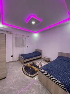 1 dormitorio con 2 camas y una iluminación púrpura en Diar ayat V1, en Taguermess