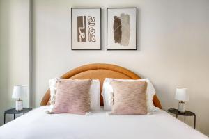 a bedroom with a white bed with three pictures on the wall at UWS 1br w doorman gym nr Central Park NYC-932 in New York