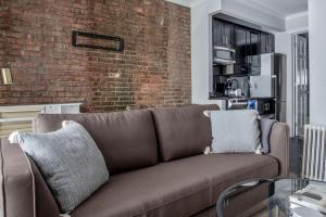 un divano marrone in un soggiorno con muro di mattoni di West Village 1BR w In-Unit WD NYC-1177 a New York