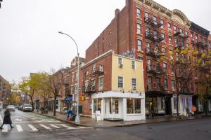 a woman crosses a street in front of a building at West Village 1BR w In-Unit WD NYC-1177 in New York