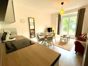 eine Küche und ein Wohnzimmer mit einem Tisch und Stühlen in der Unterkunft Le Jardin - Calme et Confort - Lac de Nantua in Nantua