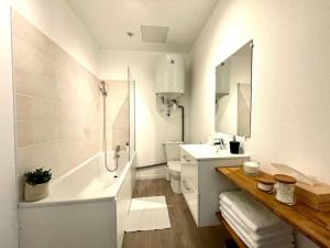 une salle de bain blanche avec une baignoire et un lavabo dans l'établissement Le Jardin - Calme et Confort - Lac de Nantua, à Nantua