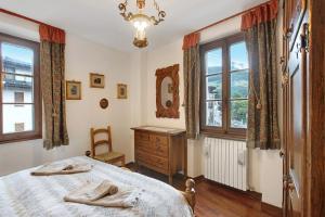 a bedroom with a bed and a dresser and windows at Bormio 3 in Bormio