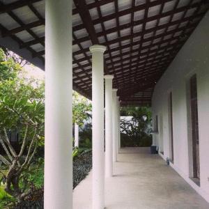 a porch with white columns and a wooden ceiling at South House-Weligama in Weligama